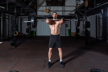 Young sweaty strong muscular fit man with big muscles holding heavy barbell weight and starting hardcore weightlifting or deadlift workout cross training in the gym real people exercising