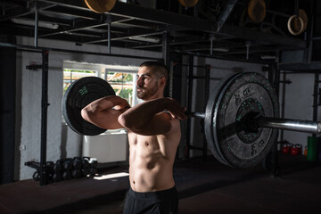 Young sweaty strong muscular fit man with big muscles holding heavy barbell weight and starting...