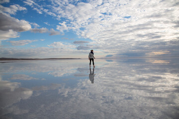 Woman walking on salt lake at sunset