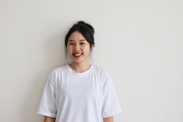 Asian young woman white t-shirt over isolated white wall smiling and looking happily