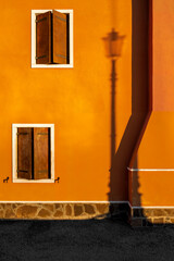 The shadow of street lamp on the orange facade, houses of Pellestrina island, Venetian lagoon, Italy