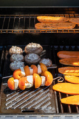An open grill with champignons, pumpkin slices, and apricots with cheese