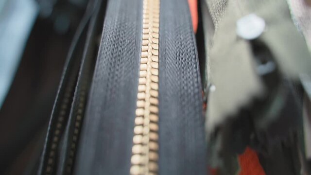 zippers hanging on the wall in a manufacturing shop. Slide fastener red, yellow, white, black color sale in stores. Texture background