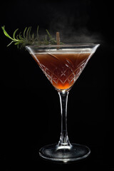 Alcoholic cocktail Cosmopolitan cocktail decorated with rosemary on martini glass and spray  on black background. Copy Space.