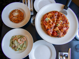 イタリアン料理　テーブルに置かれたピザ、リゾット、ニョッキ