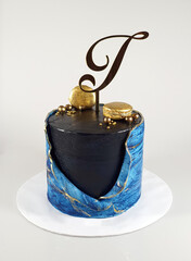Dark brown chocolate cake with a blue mixed fondant topped off with  gold colour Macaroons