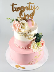 Two layered pink and white birthday cake with fresh pink and white roles