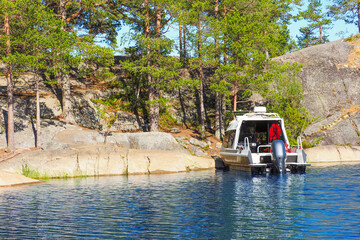 Motorboat in an idyllic natural harbor. Moored speed boat. Rocky  northern island, lake Ladoga, Karelia