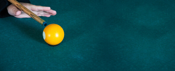 a man hits a billiard ball with a cue. serious play concept. yellow billiard ball at gunpoint