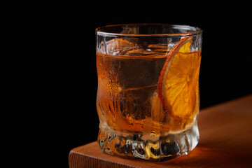 Old Fashioned cocktail on the bar on a black background