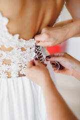 Women's hands lace up the lace corset of the bride's wedding dress. Close-up