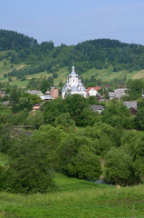 Fototapeta na wymiar Carpathian village: catholic church, country houses, gardens and hill