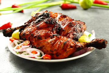 Homemade traditional Indian tandoori chicken  served in plate with fresh salads. 