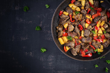 Fried chicken liver with apples and sweet peppers in iron skillet. Top view, flat lay