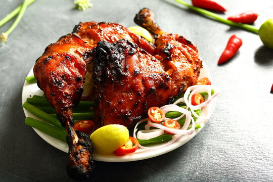 Homemade traditional Indian tandoori chicken  served in plate with fresh salads. 