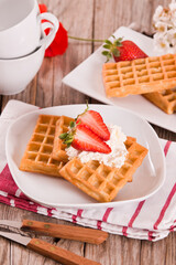 Waffles with strawberries and whipped cream.