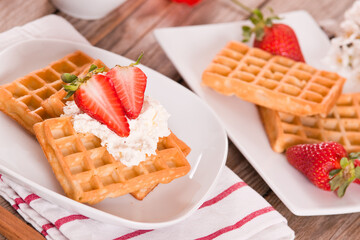 Waffles with strawberries and whipped cream.