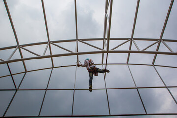 Construction workers install scaffolding and paint roof.