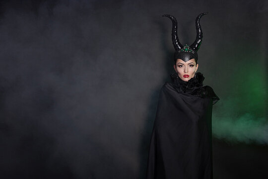A girl dressed as a fairy or a sorceress with bright makeup, maleficent.