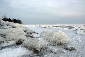 Beautiful natural phenomenon - ice covered stones on the coast at the Vistula mouth to the Baltic, Sobieszewska Island, Poland