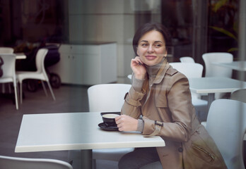Beautiful attractive stunning brunette woman with a stylish short haircut in a beige trench coat...