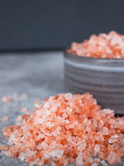 Fototapeta na wymiar Heap of pink Himalayan rock coarse salt on the table next to a gray bowl with salt