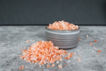 Fototapeta na wymiar Heap of pink Himalayan rock coarse salt on the table next to a gray bowl with salt