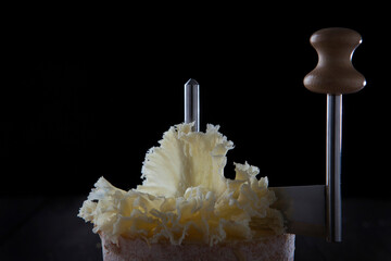 Thin shavings of tete de moine cheese. Special girolle knife. Cheese on wooden round board....