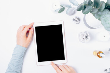 Female hands using tablet computer next to feminine accessories
