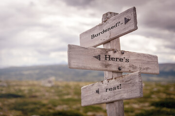 burdened heres rest text on wooden sign outdoors in nature. Religious and christianity quotes.