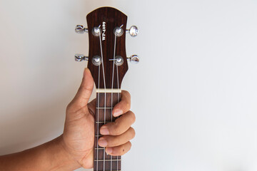 hand hold neck of ukulele it for playing on white background
