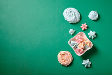 Multicolored meringue on a green background, top view
