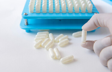 White pill capsules in hand wearing white medical gloves on white background