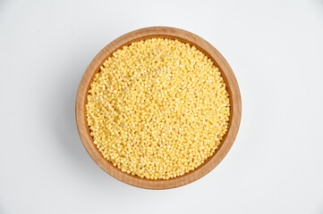 millet grains in a wooden bowl on a white background