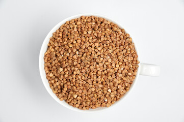 buckwheat grains in a ceramic cup on a white background