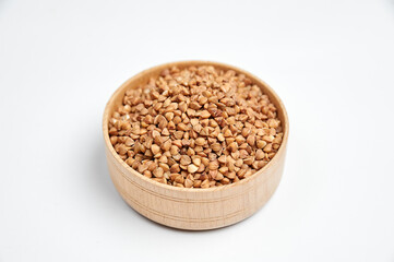 buckwheat grains in a wooden bowl on a white background