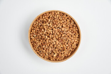 buckwheat grains in a wooden bowl on a white background