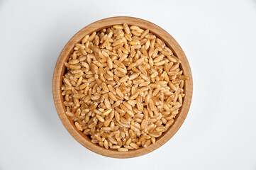 peeled wheat grain in a wooden bowl on a white background
