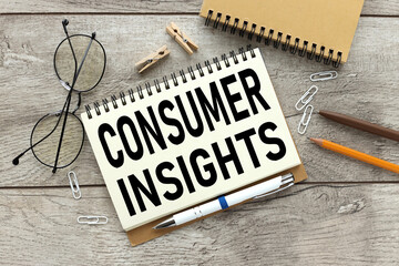 Consumer Insights. text on white paper. the inscription on the notebook. business concept. notepad on a wooden background. glasses, pen, pencil