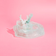 Minimal creative composition with plastic bag and white reindeer. Pastel pink Christmas concept.