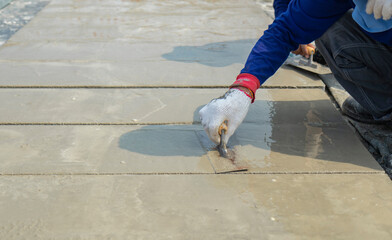 Motion blur white cloth gloves of workers are holding the trowel to smooth the cement face on floor in construction area.
