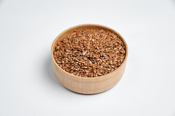 flax grain in a wooden bowl on a white background