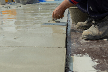 hand of worker holding steel trowel in hands on cement surface . for ground is being smoothed