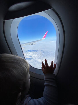 Little baby boy points his finger at the sky through the window. Mobile photo