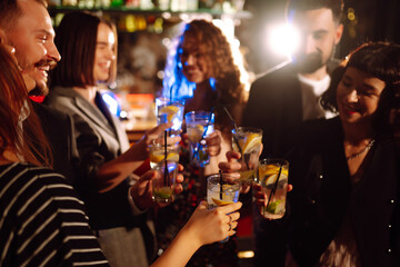 Cheering and drinking cocktails. Group of people partying in a nightclub and toasting drinks with cocktails. Party, celebration, drink, birthday concept.