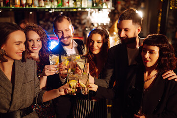 Cheering and drinking cocktails. Group of people partying in a nightclub and toasting drinks with cocktails. Party, celebration, drink, birthday concept.