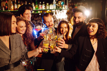 Cheering and drinking cocktails. Group of people partying in a nightclub and toasting drinks with cocktails. Party, celebration, drink, birthday concept.