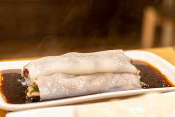 Chinese rice noodle roll with shrimp and minced pork on white plate.