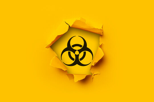 Bright yellow torn paper cardboard inside in a hole sign of radiation on a yellow background.