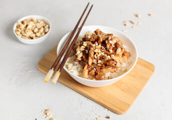 Bowl with chinese food. Kung pao, rice with chicken fillet in sauce. Close-up on a light background, horizontal